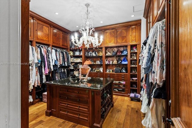 walk in closet featuring light wood-type flooring and a chandelier