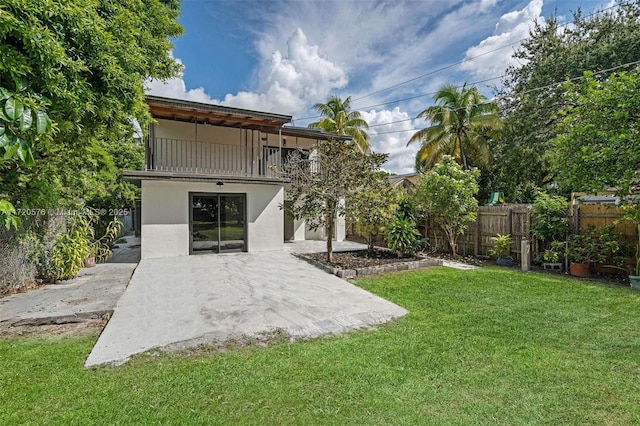 rear view of house with a yard, a patio, and a balcony