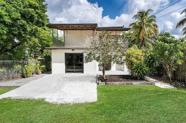 rear view of house featuring a lawn, a patio area, and a balcony