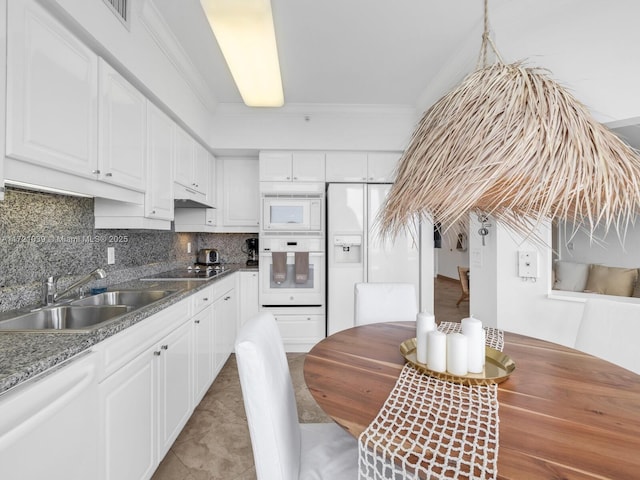 kitchen featuring dark stone countertops, white cabinetry, sink, and white appliances