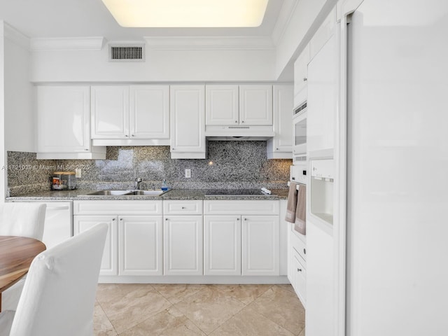 kitchen with tasteful backsplash, sink, white cabinets, and black electric stovetop