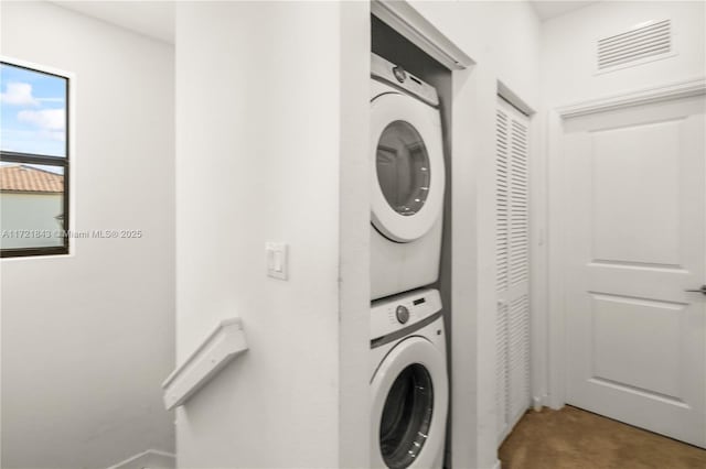 clothes washing area featuring stacked washer and clothes dryer