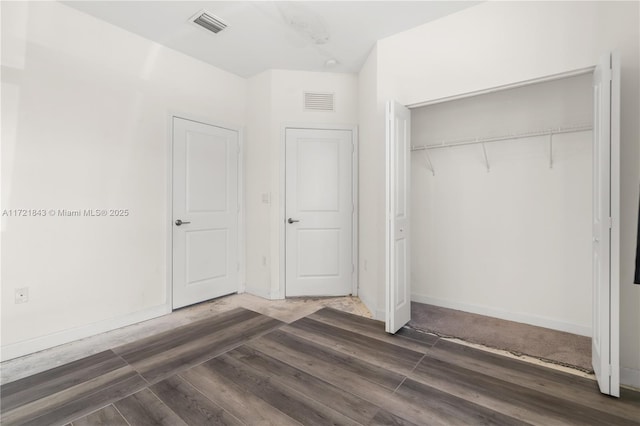 unfurnished bedroom with a closet and dark wood-type flooring