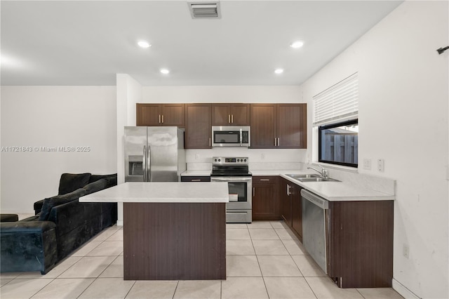 kitchen with dark brown cabinetry, sink, a center island, light tile patterned floors, and appliances with stainless steel finishes