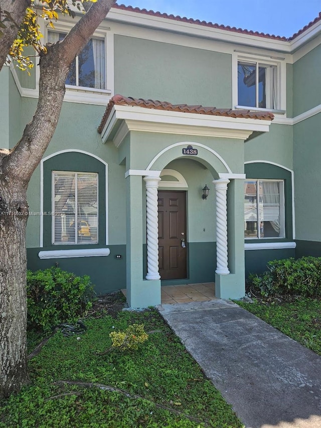 entrance to property featuring a tile roof and stucco siding