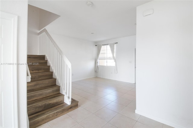 stairs with baseboards and tile patterned floors