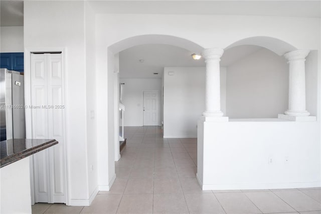 corridor featuring light tile patterned flooring and decorative columns