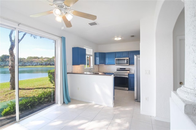 kitchen with a water view, light tile patterned floors, blue cabinetry, tasteful backsplash, and stainless steel appliances