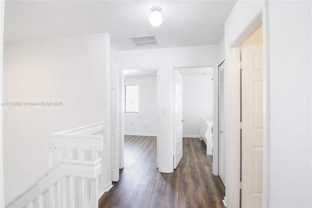 corridor featuring dark wood-style floors, baseboards, and visible vents