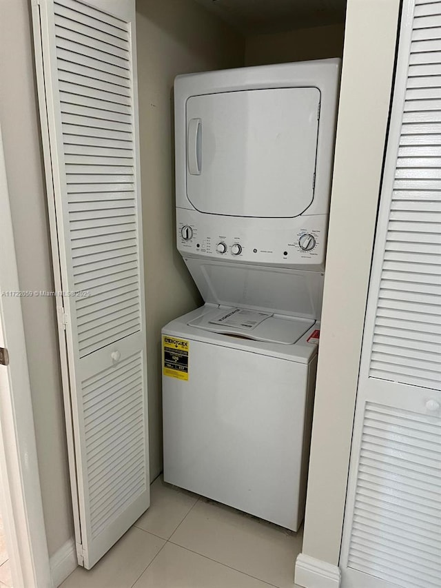 clothes washing area with light tile patterned floors and stacked washing maching and dryer