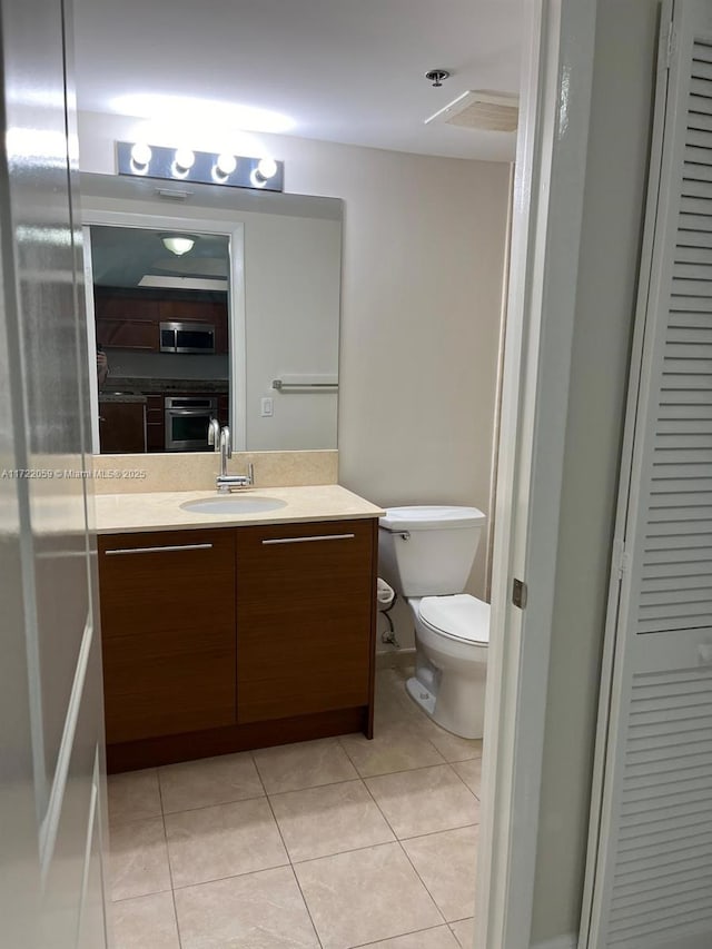 bathroom featuring toilet, vanity, and tile patterned floors