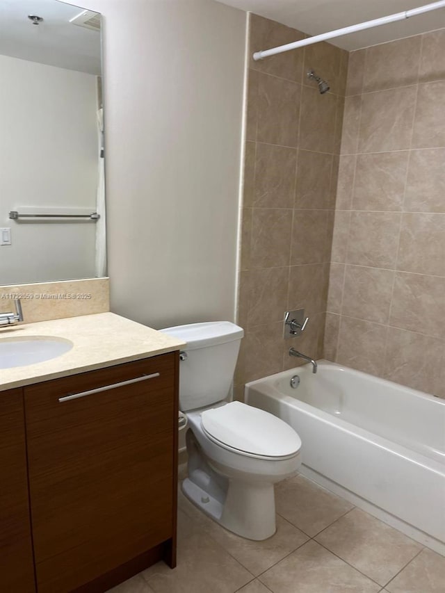 full bathroom with tile patterned flooring, tiled shower / bath combo, toilet, and vanity