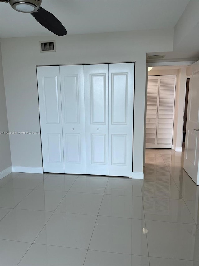 unfurnished bedroom with light tile patterned floors, a closet, and ceiling fan