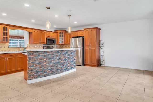 kitchen with appliances with stainless steel finishes, a center island, light tile patterned floors, and decorative light fixtures