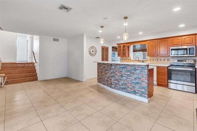 kitchen with pendant lighting, light tile patterned floors, sink, appliances with stainless steel finishes, and backsplash