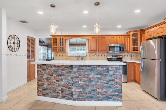 kitchen with sink, light tile patterned floors, appliances with stainless steel finishes, a kitchen island, and backsplash