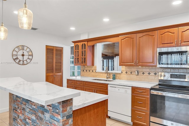 kitchen featuring a kitchen island, pendant lighting, sink, stainless steel appliances, and light stone countertops