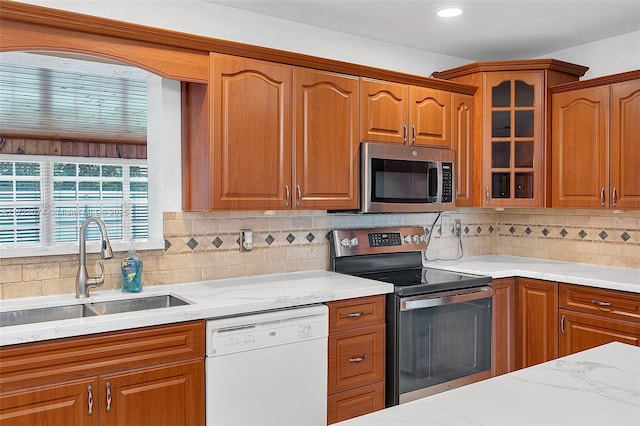 kitchen with light stone countertops, appliances with stainless steel finishes, sink, and backsplash