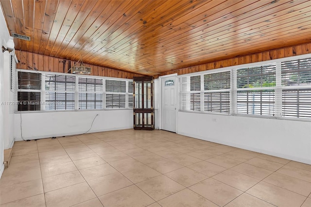 empty room with light tile patterned flooring, vaulted ceiling, and wooden ceiling