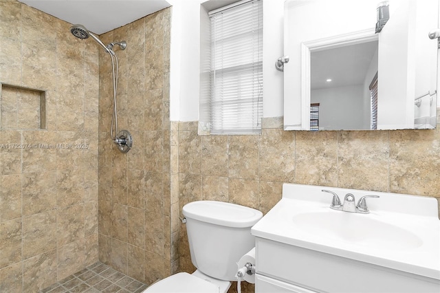 bathroom featuring tiled shower, vanity, toilet, and tile walls