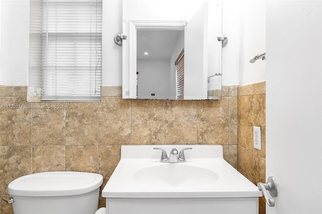 bathroom featuring vanity, tile walls, and toilet