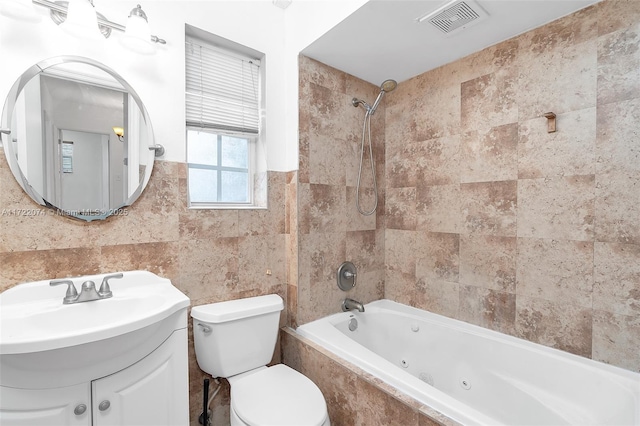 full bathroom featuring vanity, toilet, tiled shower / bath combo, and tile walls