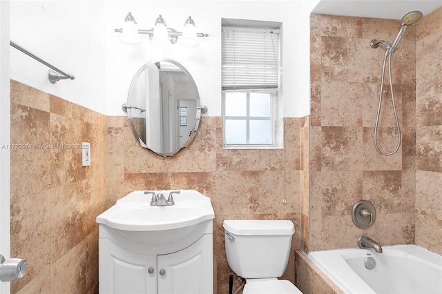 full bathroom featuring vanity, toilet, tiled shower / bath combo, and tile walls