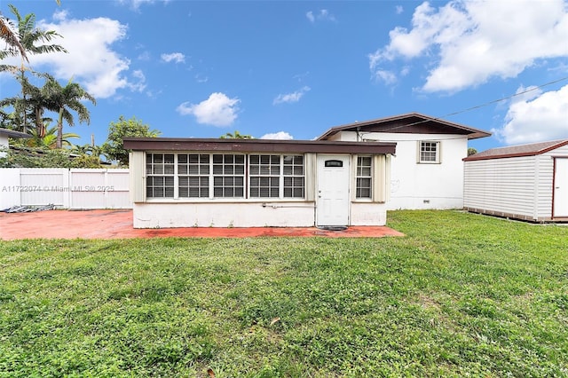 back of property featuring a storage shed, a yard, and a patio area