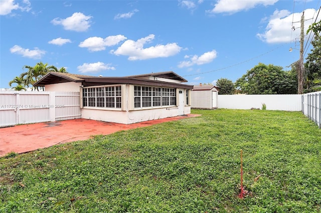 back of property featuring a shed, a patio area, and a lawn