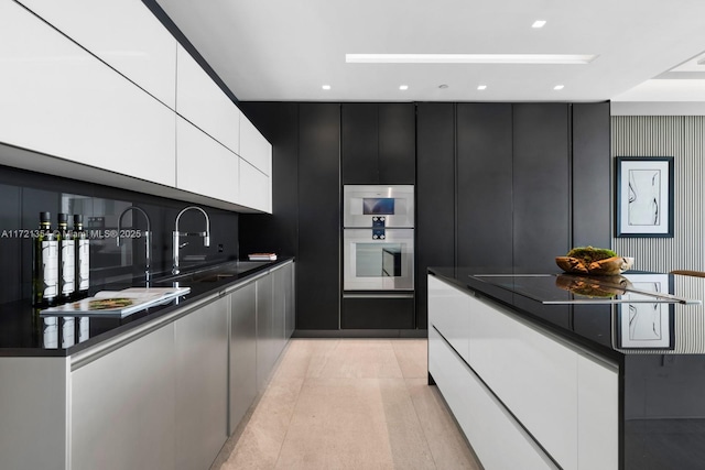 kitchen with white cabinetry, sink, double oven, dark stone countertops, and black stovetop