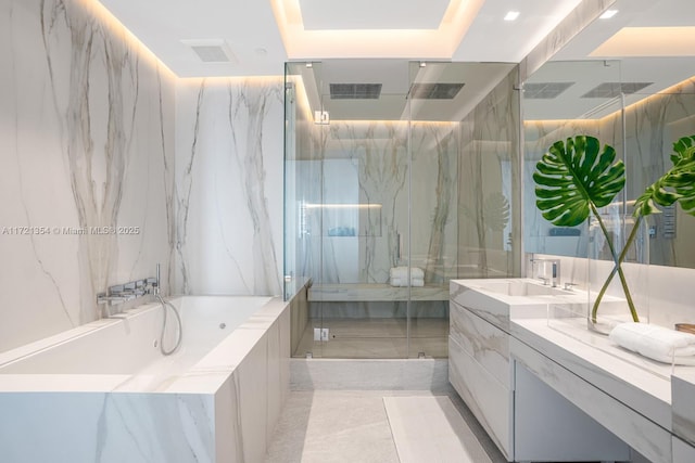 bathroom with vanity, shower with separate bathtub, and tile walls