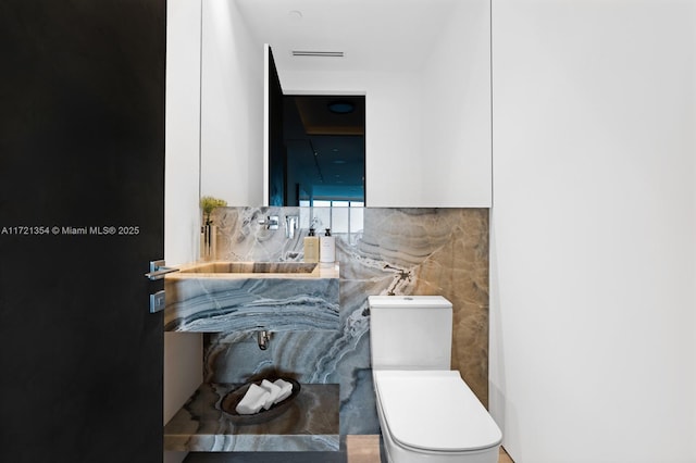 half bath featuring toilet and tile walls