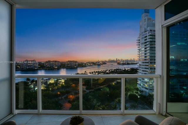 balcony at dusk with a water view and a city view
