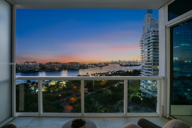 balcony at dusk featuring a water view