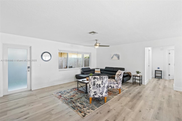 living room with ceiling fan, light hardwood / wood-style flooring, and a textured ceiling