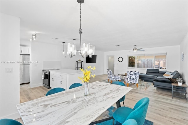 dining space with ceiling fan with notable chandelier and light hardwood / wood-style floors