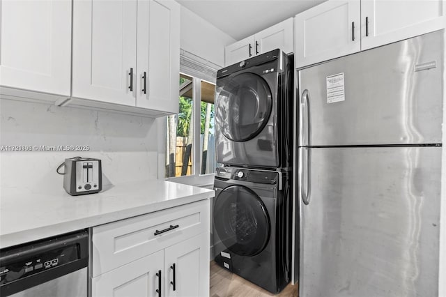 washroom with light hardwood / wood-style floors and stacked washer / drying machine