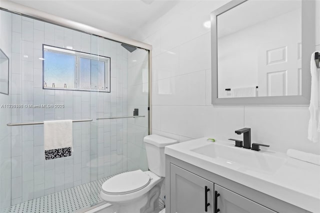 bathroom with vanity, toilet, a shower with shower door, and tile walls