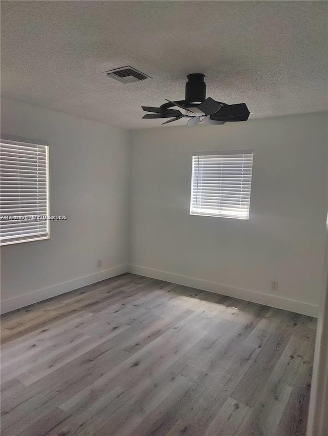 unfurnished room featuring a textured ceiling and light wood-type flooring