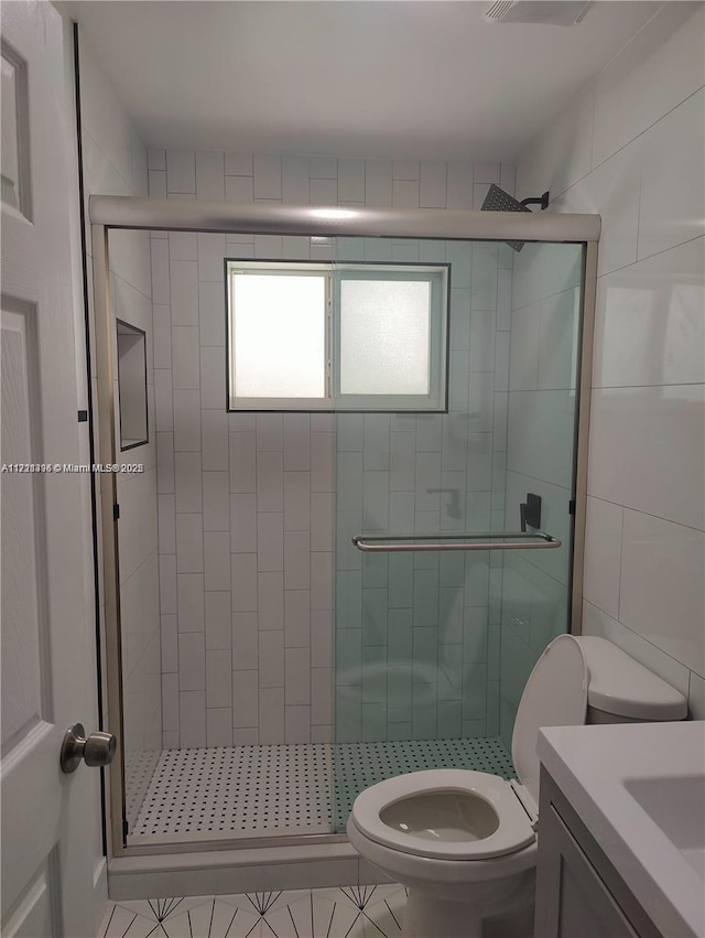 bathroom featuring tile patterned flooring, vanity, toilet, and a shower with door