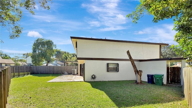 rear view of property featuring a lawn, a patio area, and central AC unit