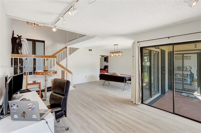 office area with light hardwood / wood-style flooring, a textured ceiling, and track lighting