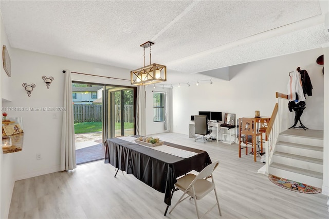 dining space with track lighting, a textured ceiling, and light hardwood / wood-style flooring