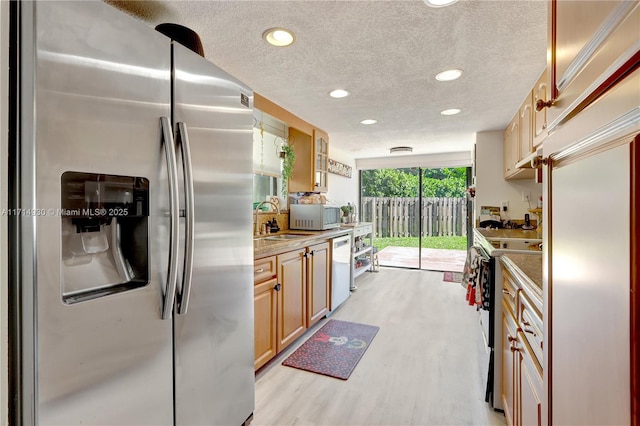 kitchen featuring a textured ceiling, light hardwood / wood-style floors, white appliances, and sink