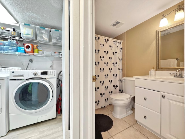 laundry room with light tile patterned floors, a textured ceiling, washer and clothes dryer, and sink