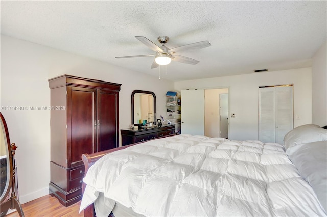 bedroom featuring ceiling fan, a textured ceiling, and light hardwood / wood-style flooring