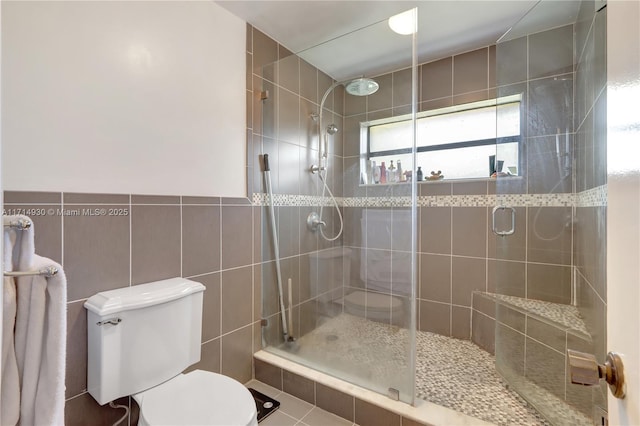 bathroom with tile patterned flooring, toilet, an enclosed shower, and tile walls