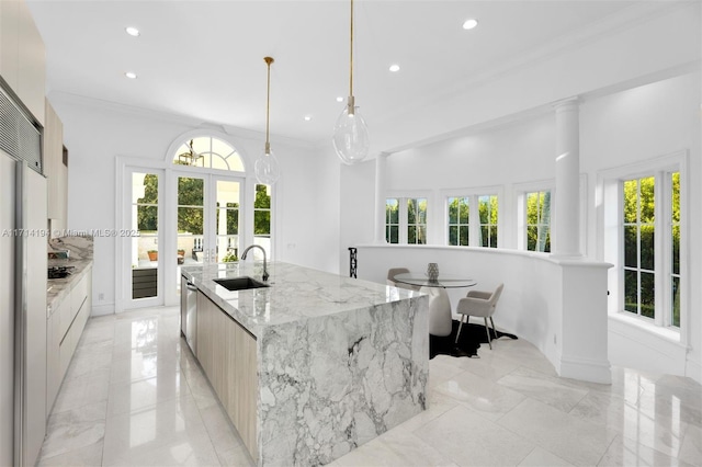 kitchen featuring light stone counters, stainless steel dishwasher, sink, a large island with sink, and hanging light fixtures