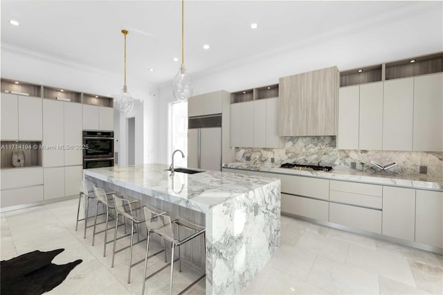 kitchen with paneled fridge, stainless steel gas cooktop, sink, pendant lighting, and an island with sink