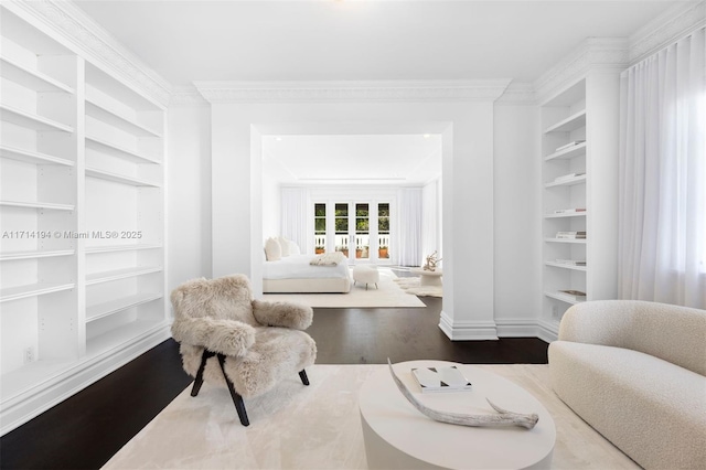 living room with built in shelves, wood-type flooring, and crown molding